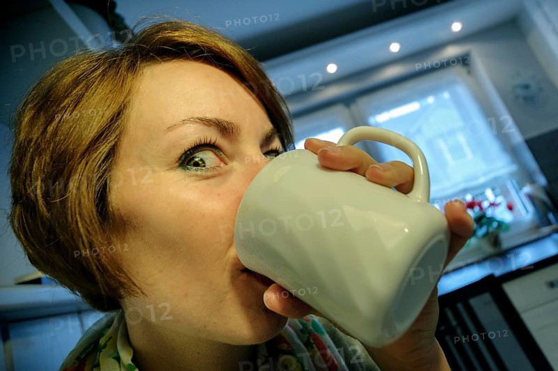 Young woman drinking coffee enthusiastically