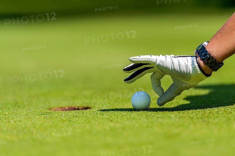 Finger flicking the golf ball into the hole