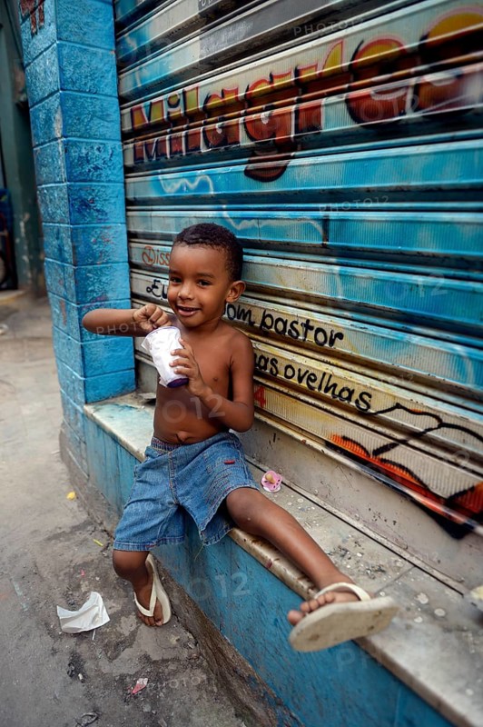 Boy eating from a tub of ice cream in a slum or favela