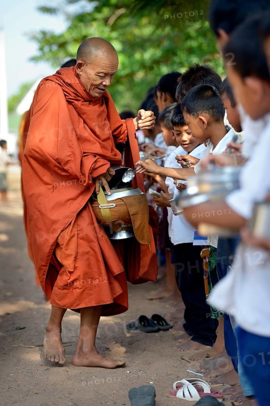 Children donating food and money to a Buddhist monk
