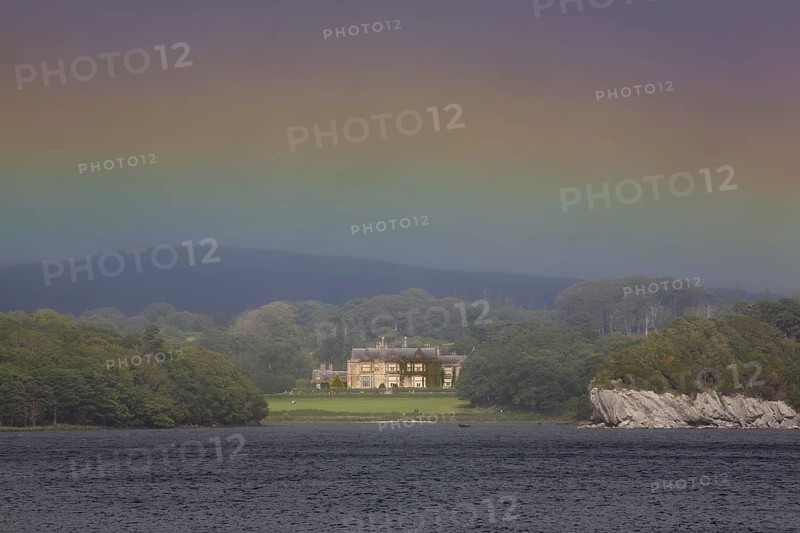 Muckross House on Muckross Lake with rainbow colors in the sky
