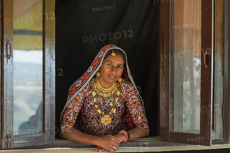 Ahir woman in traditional colorful clothes looking out of a window