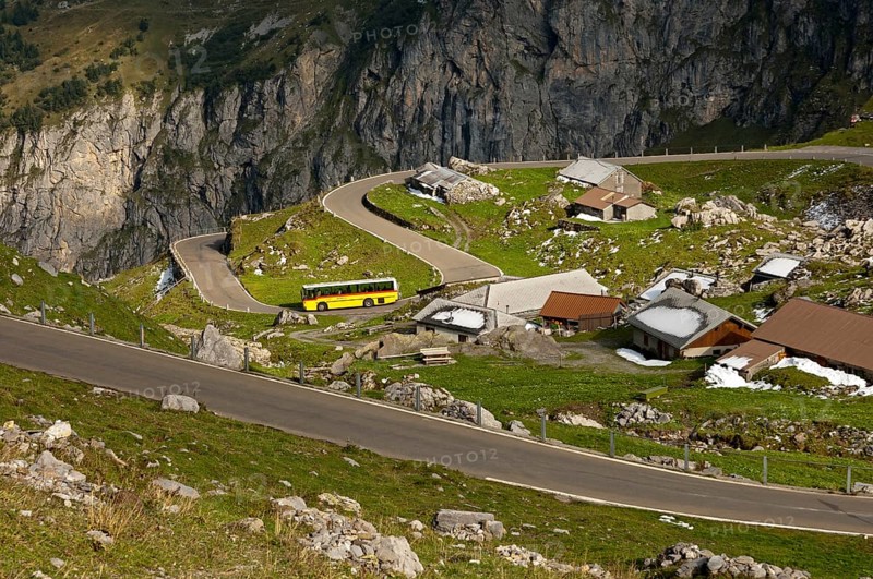 Yellow bus from the PostAuto Schweiz AG in a hamlet on the serpentine-rich Klausen Pass road