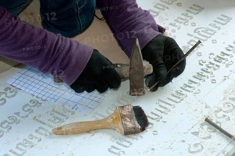 Stonemason chiselling Khmer characters into a gravestone in a stone cutting factory