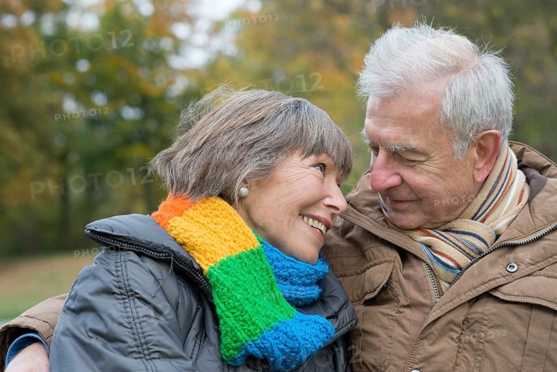 Senior couple sitting arm in arm on a park bench