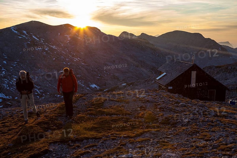 Two hikers at Edelweisserhuette refuge at sunset