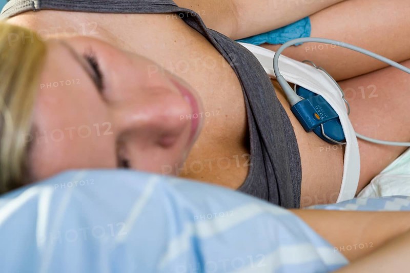 Pregnant woman resting on a delivery bed during childbirth connected to a cardiotocography or CTG