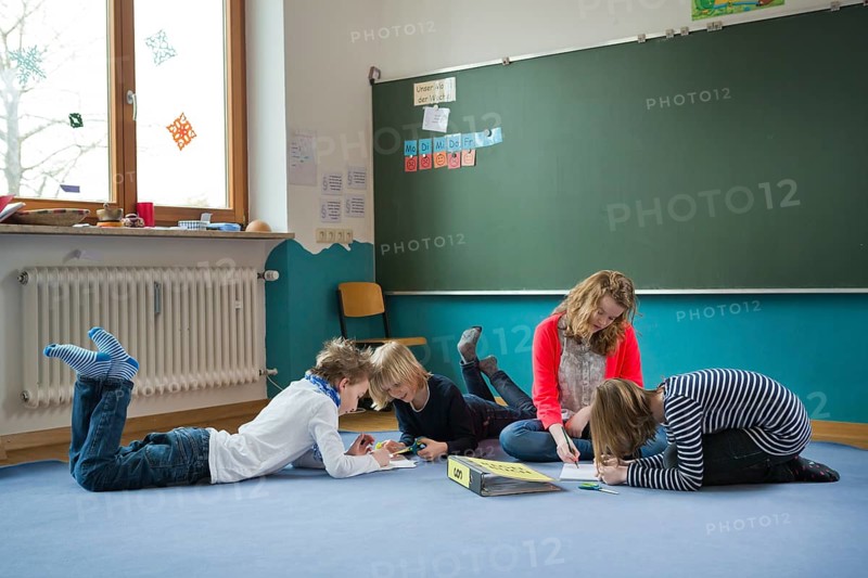 Students at an independant school sitting and lying to work on the ground