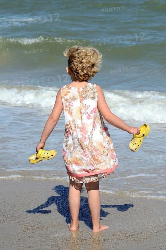 Kleines Madchen am Strand sieht auf die Wellen
