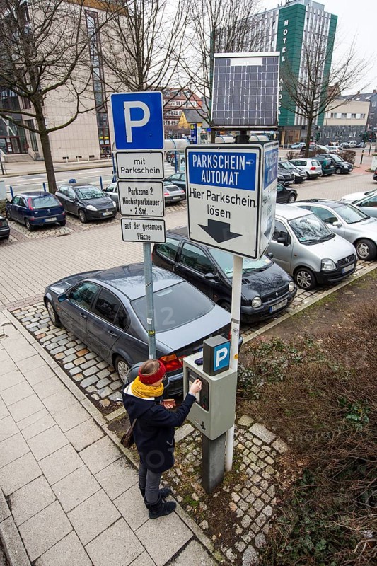 Woman purchasing a parking ticket from a solar powered parking ticket vending machine