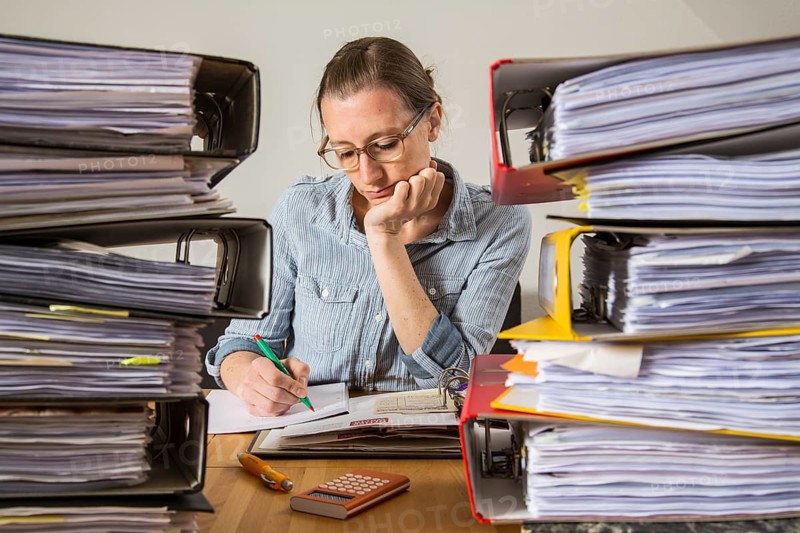 Woman working at a desk between stacks of files