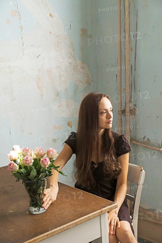 Young woman sitting at a table with flowers in a vase