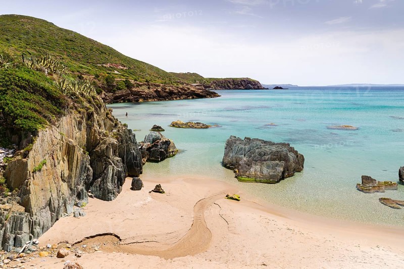 A creek running through the sand of the Spiaggia di Planusartu bay into the sea
