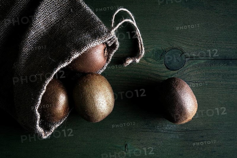 Kiwi fruits in jute sack lying on a wooden table