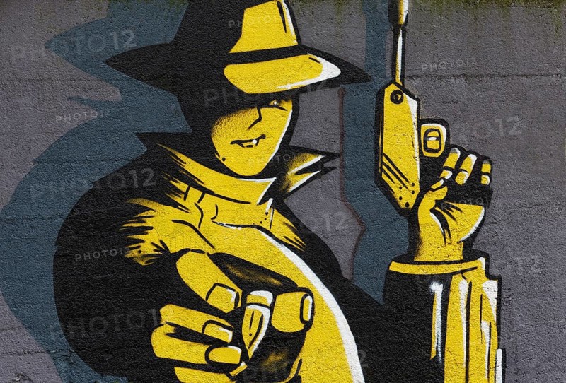 Man holding a pistol and holding a bullet in his outstretched hand