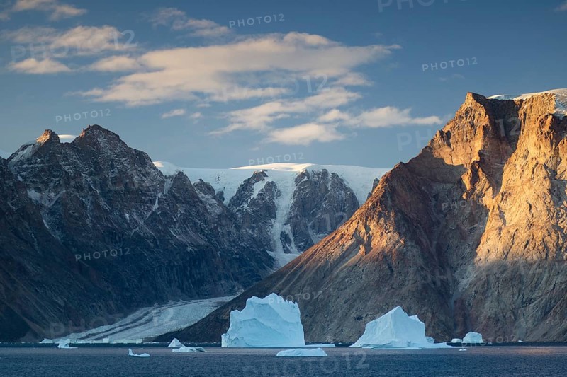 Icebergs in front of the mountain and glacier scenery in Vest Frederiksdal in the morning light