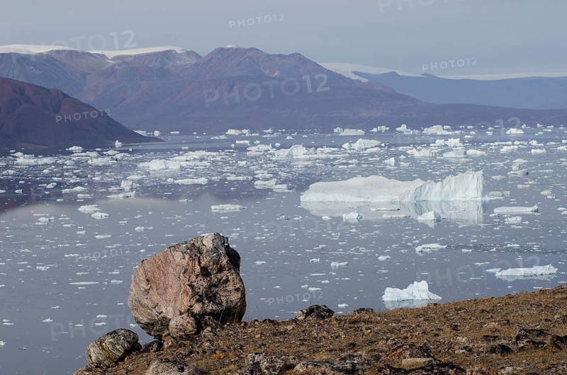 Rocky landscape of the island of Sorte Oer in front of drifting icebergs