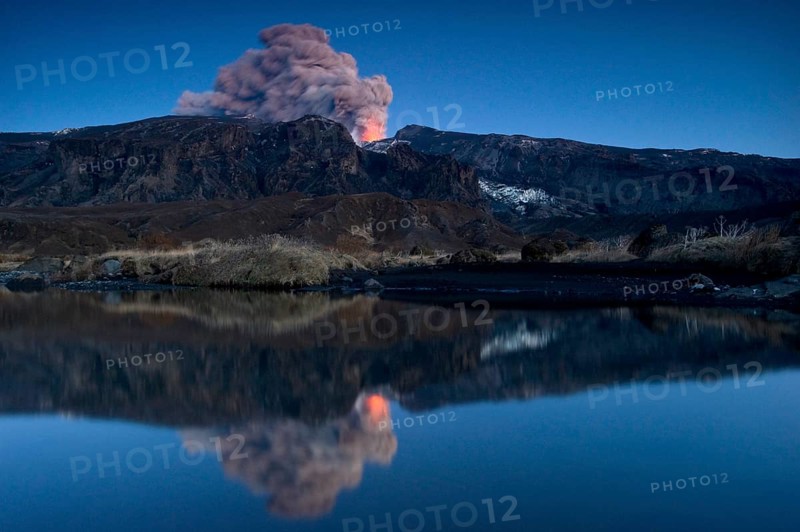 Eruption of Eyjafjallajoekull volcano with its reflection