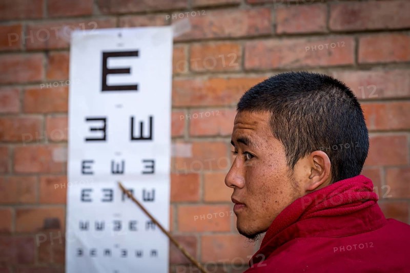 A monk from Amitabha Monastery carrying out a vision test for poor villagers