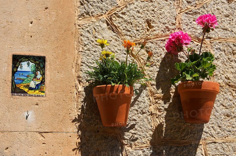 Holy image and a flower pots on a house wall