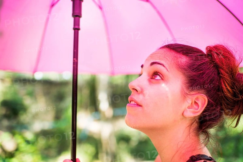 Young woman with a pink umbrella in the sun