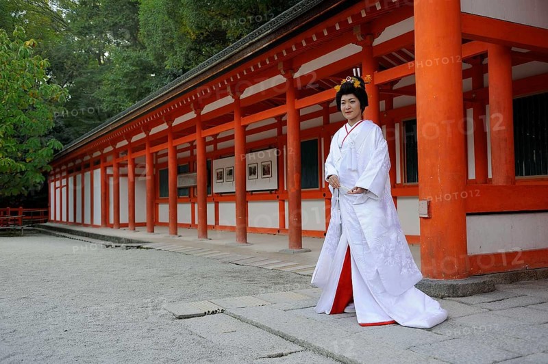 Bride in a traditional kimono with brocade holding a fan
