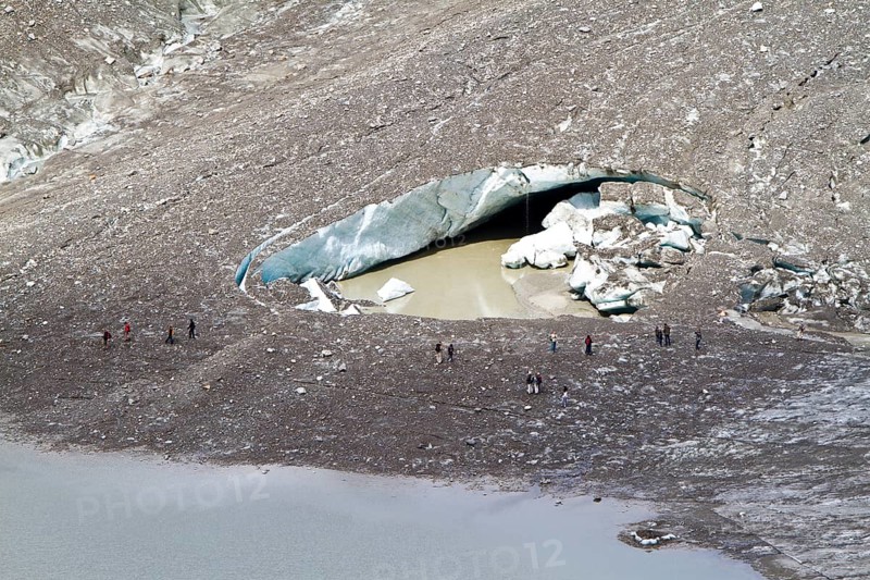 Hikers at the hole of collapsed ice in Pasterze Glacier