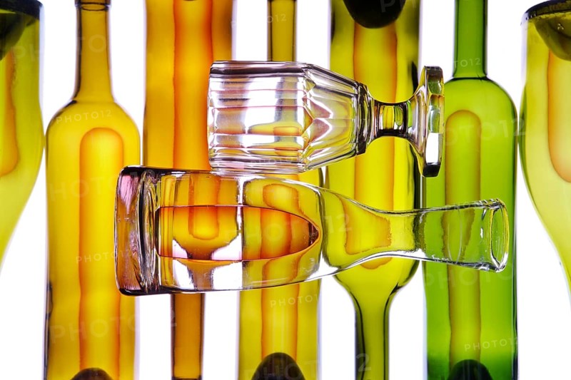 Carafe and wine glass in front of wine bottles