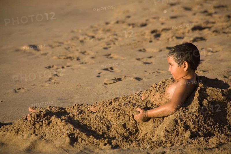 Young covering himself with the sand on the beach