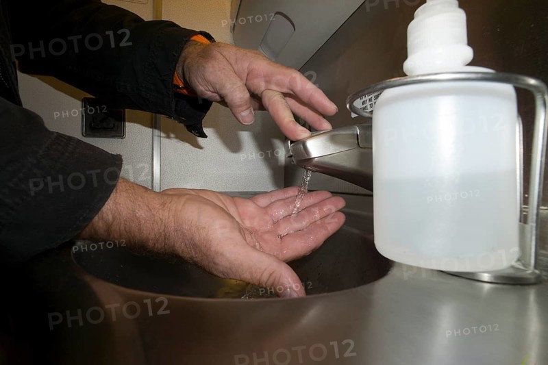 A passenger washing his hands in the lavatory of an airplane