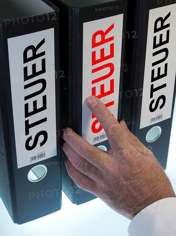 Hand reaching for file folders labeled 'Steuer'
