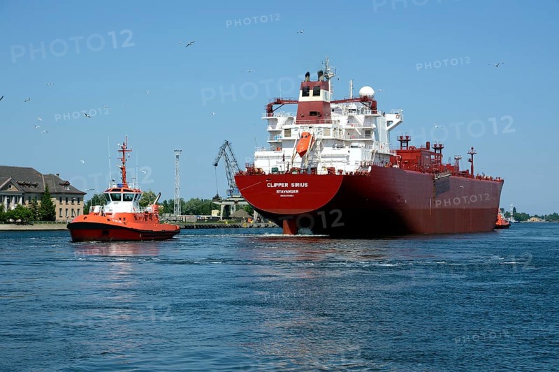 A cargo ship is towed from the Gdansk shipyard by a tug boat