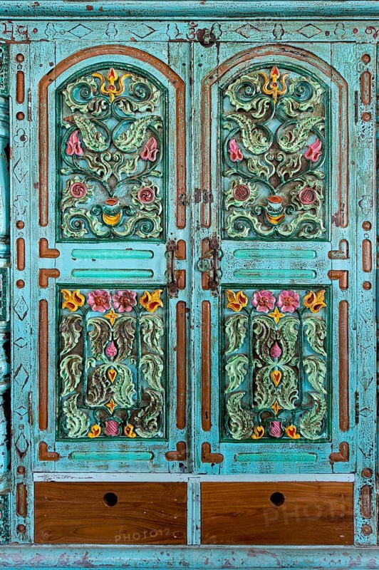 Ornately carved flowers in a turquoise cabinet door