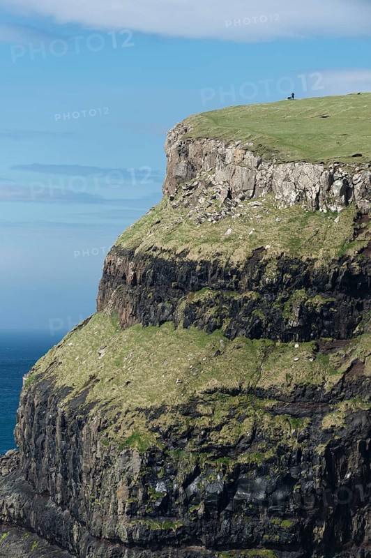 Man with a dog at the top of a cliff