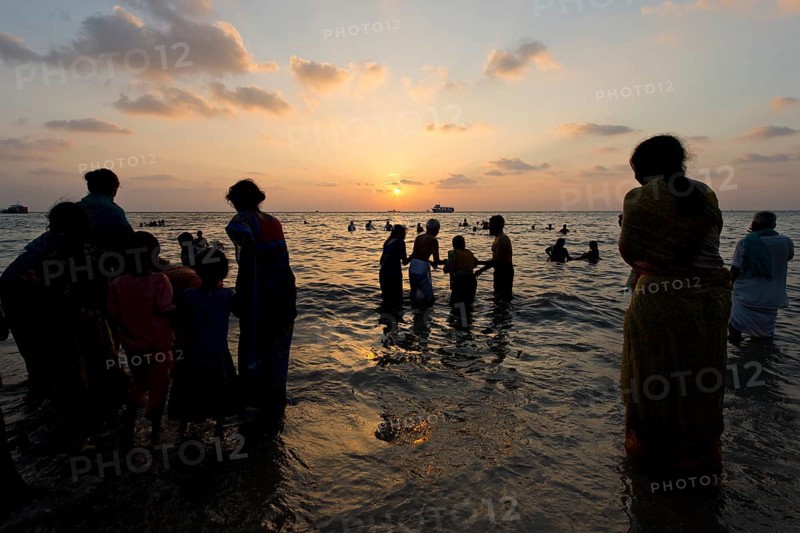 Hindu pilgrims taking a holy bath in the sea at sunrise