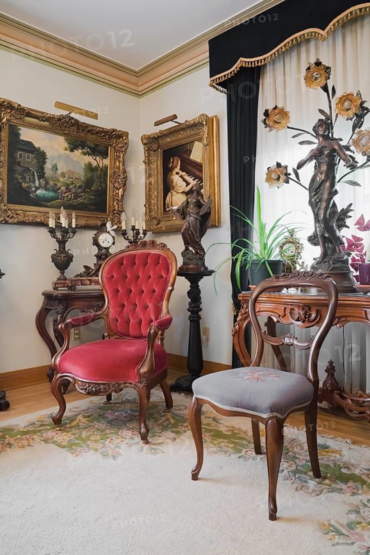 Antique chairs and furnishings adorn a living room inside a Victorian mansion