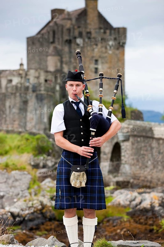 Bagpiper standing in front of Eilean Donan Castle