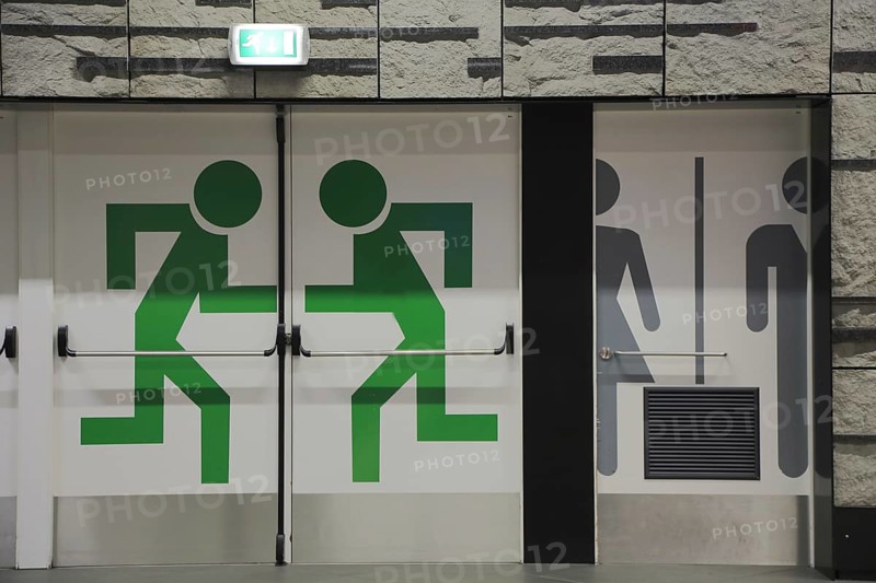 Emergency exit and toilet pictograms on doors in the station at the airport