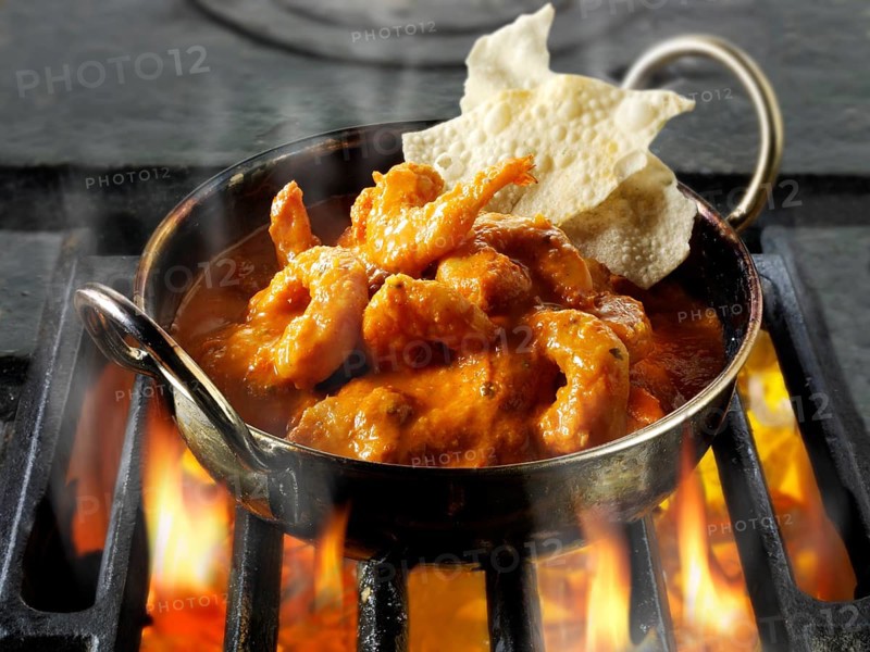 Indian prawn Makhani curry being cooked over hot charcoals