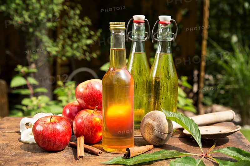 Apples with apple cider vinegar and apple juice on a wooden box in the garden
