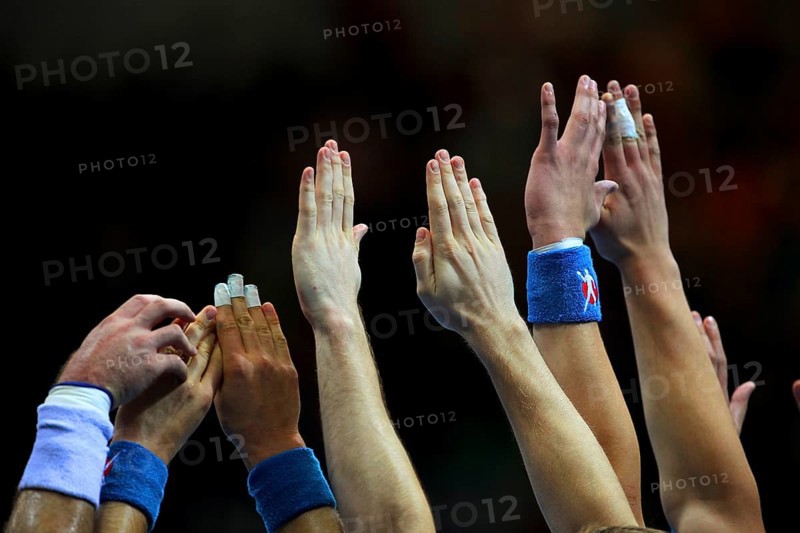 Handball players stretch their hands up to fend off a free-kick