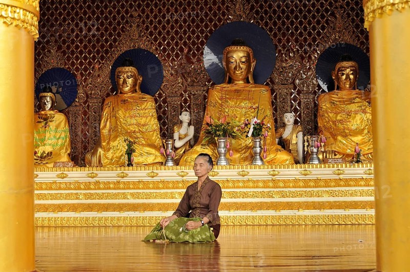 Woman meditating in front of Buddha statues