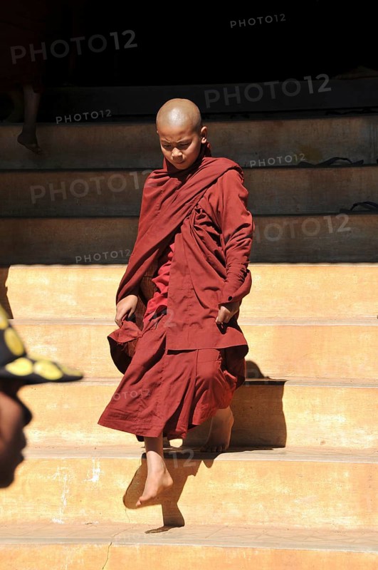 Young Buddhist monk stepping out of a monastery