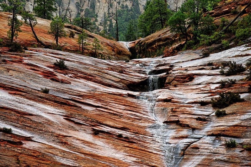 Water draining off over red Navajo sandstone rocks after a rainstorm near Canyon Overlook