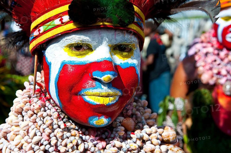 Woman in a colourfully decorated costume with face paint at the traditional sing-sing gathering