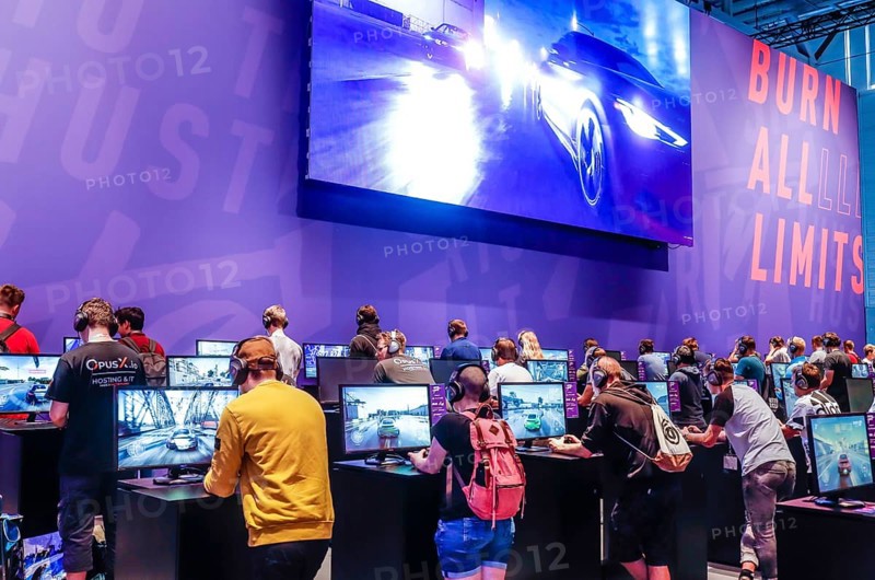 Teenagers at Need for Speed car racing game in front of screens