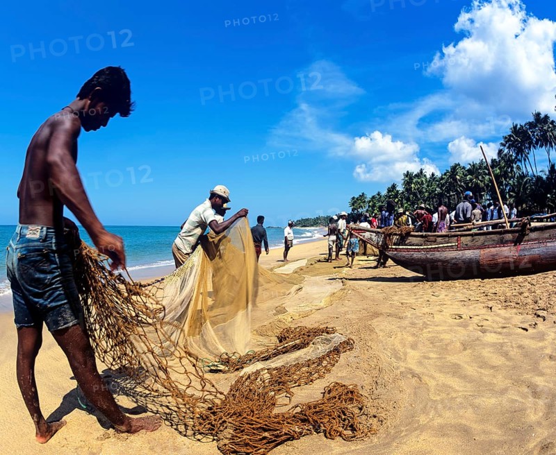 Fishermen repairing a fishing net on the beach