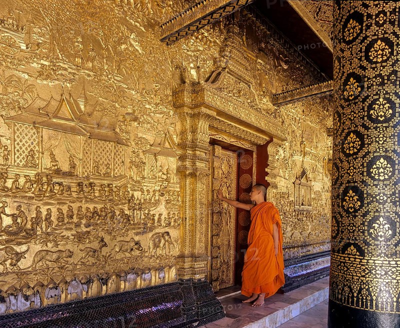 Monk standing at the gilded doors of Wat Mai Temple