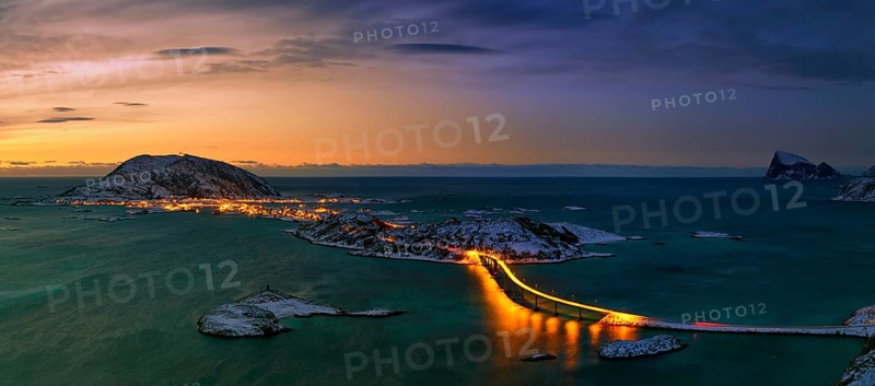 Fjord with an illuminated bridge in winter at sunset