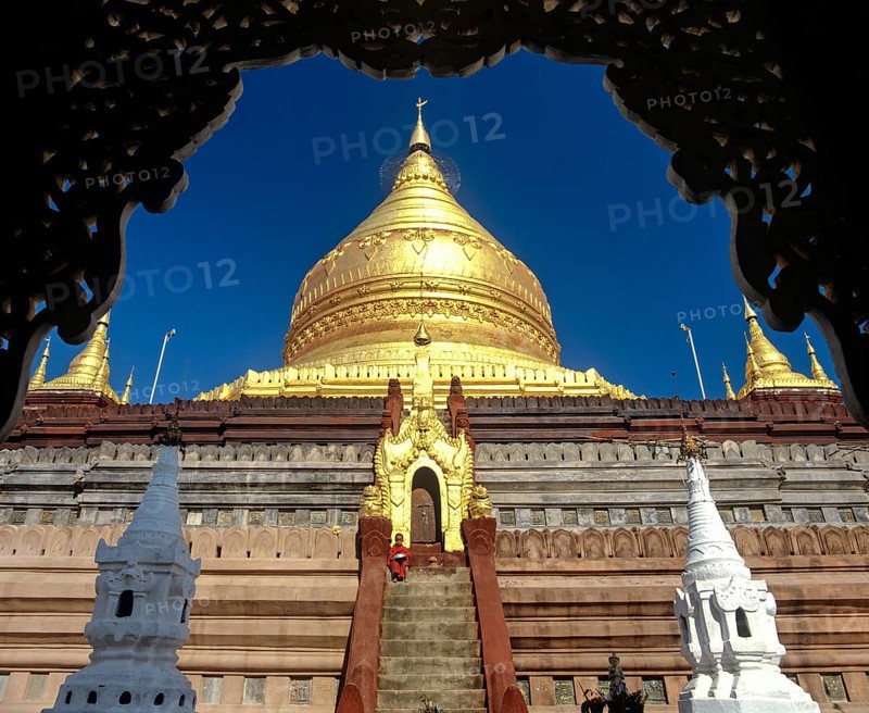 Monk on the stairs of Shwezigon Pagoda with its golden chedi